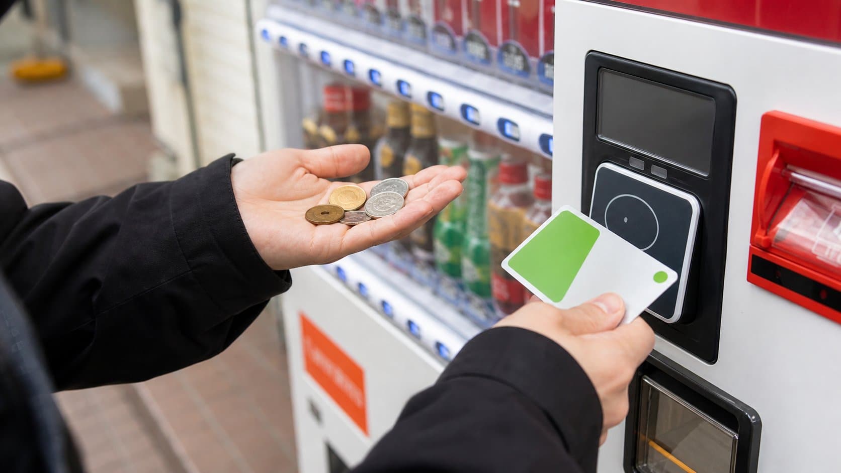 A traveler comparing coins with a transit IC card at a Japanese vending machine