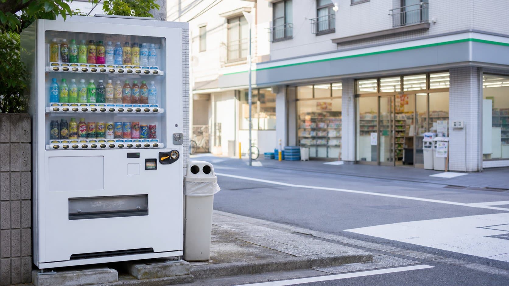 A Japanese drink vending machine across from a neighborhood convenience store